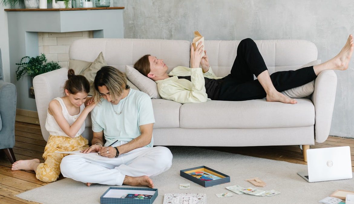 Father and daughter bonding in cozy living room with books and games, creating joyful family moments.