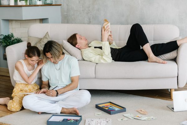 Father and daughter bonding in cozy living room with books and games, creating joyful family moments.